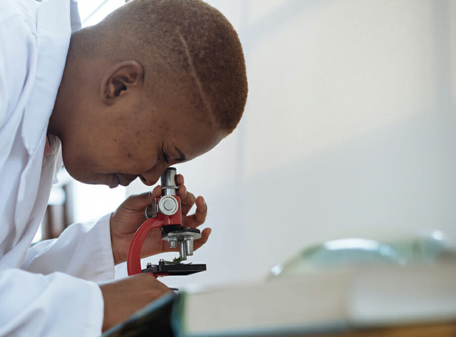 A person looks into a microscope in a lab.