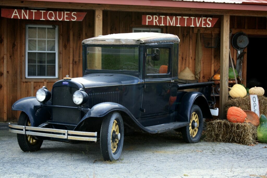 A vintage truck parked in front of an antique store with vintage supplies.