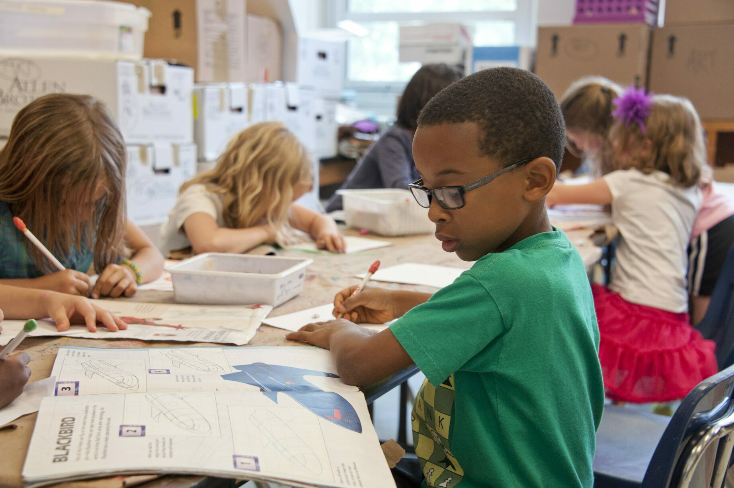 Children use pencils to work on worksheets in a library or classroom.