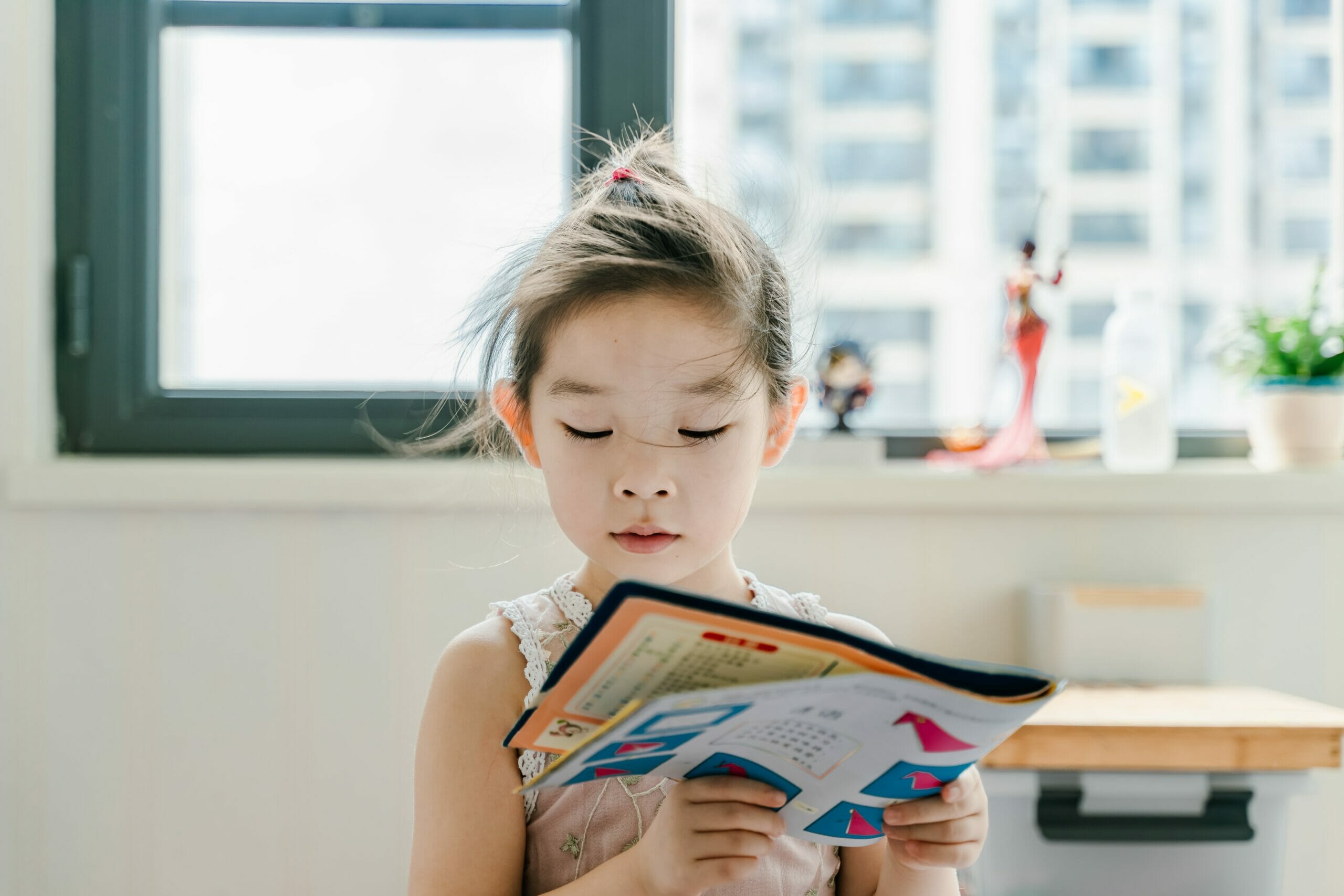 Young child looks at a magazine in a well lit building.