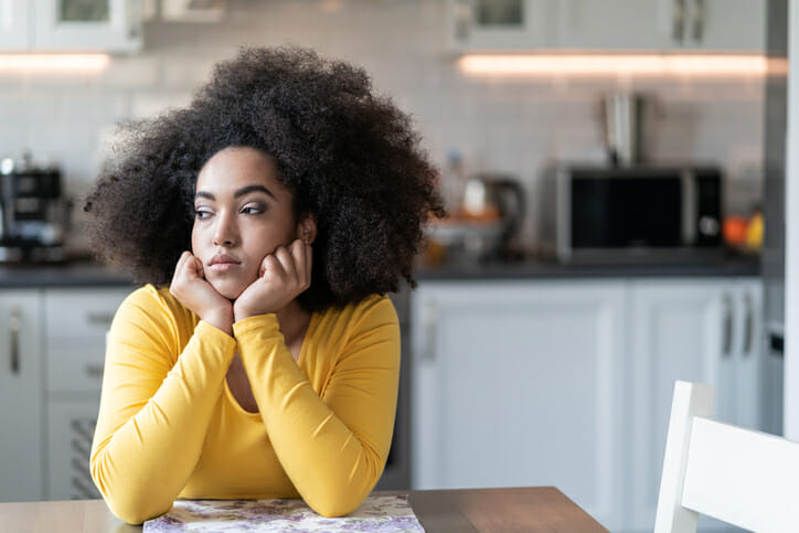 Depressed person at home sits at a kitchen table.