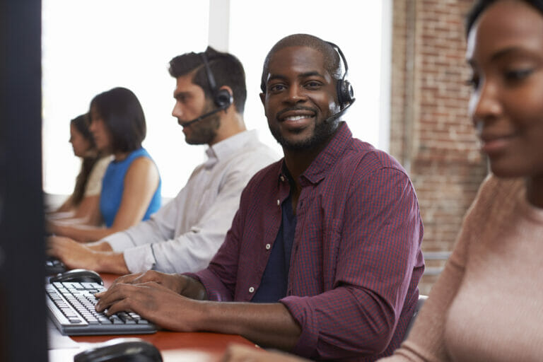 Staff in a busy call center work at computers.