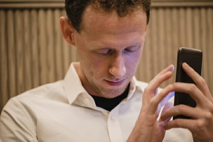 A blind person holds and touches a mobile phone.