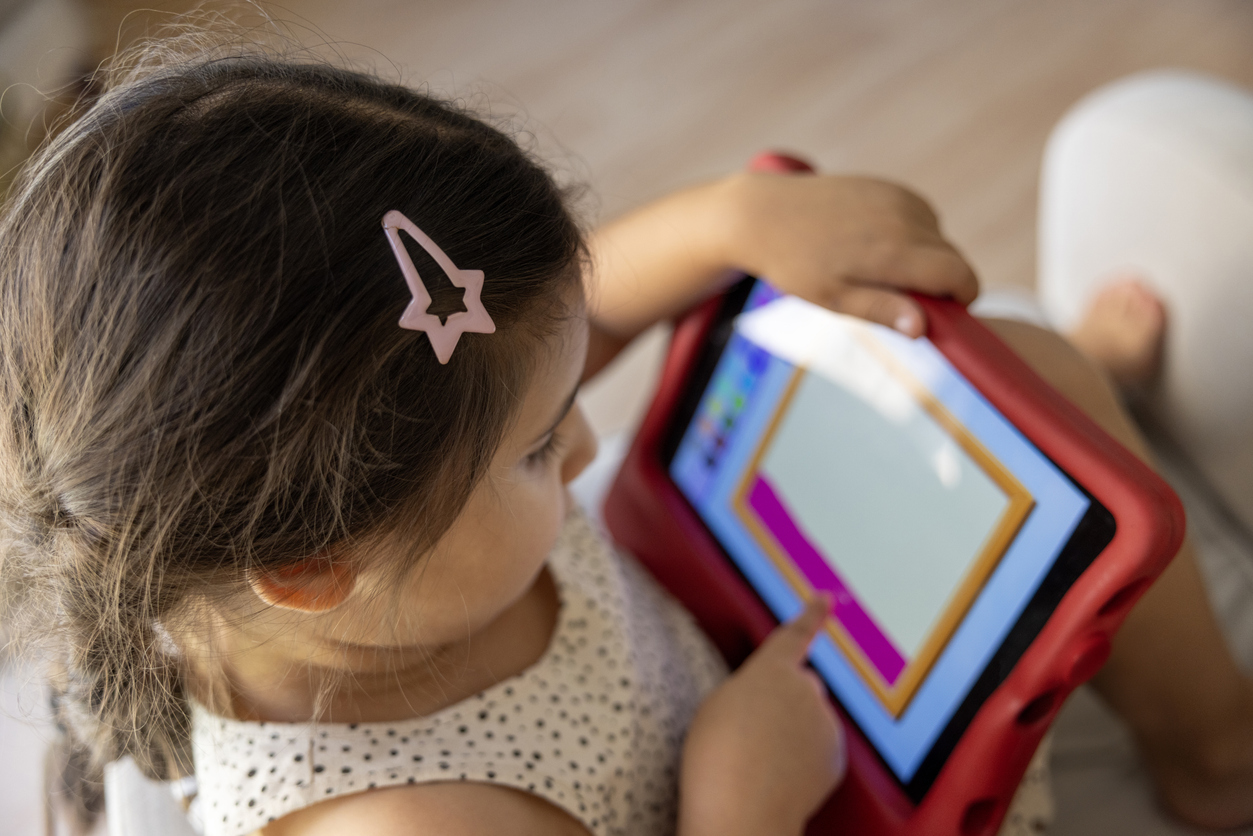 a little girl playing with a tablet on the couch