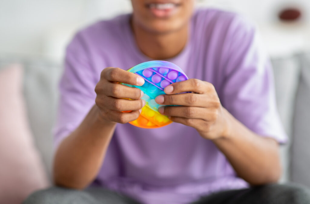 Closeup view of teenager playing with a fidget pop toy.